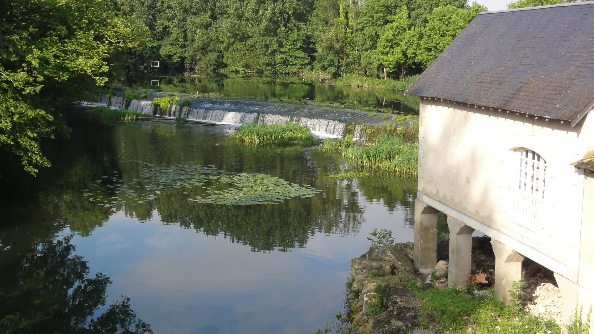 Le moulin et les berges du Clain à Chasseneuil-du-Poitou, chute d'eau bordée de verdure
