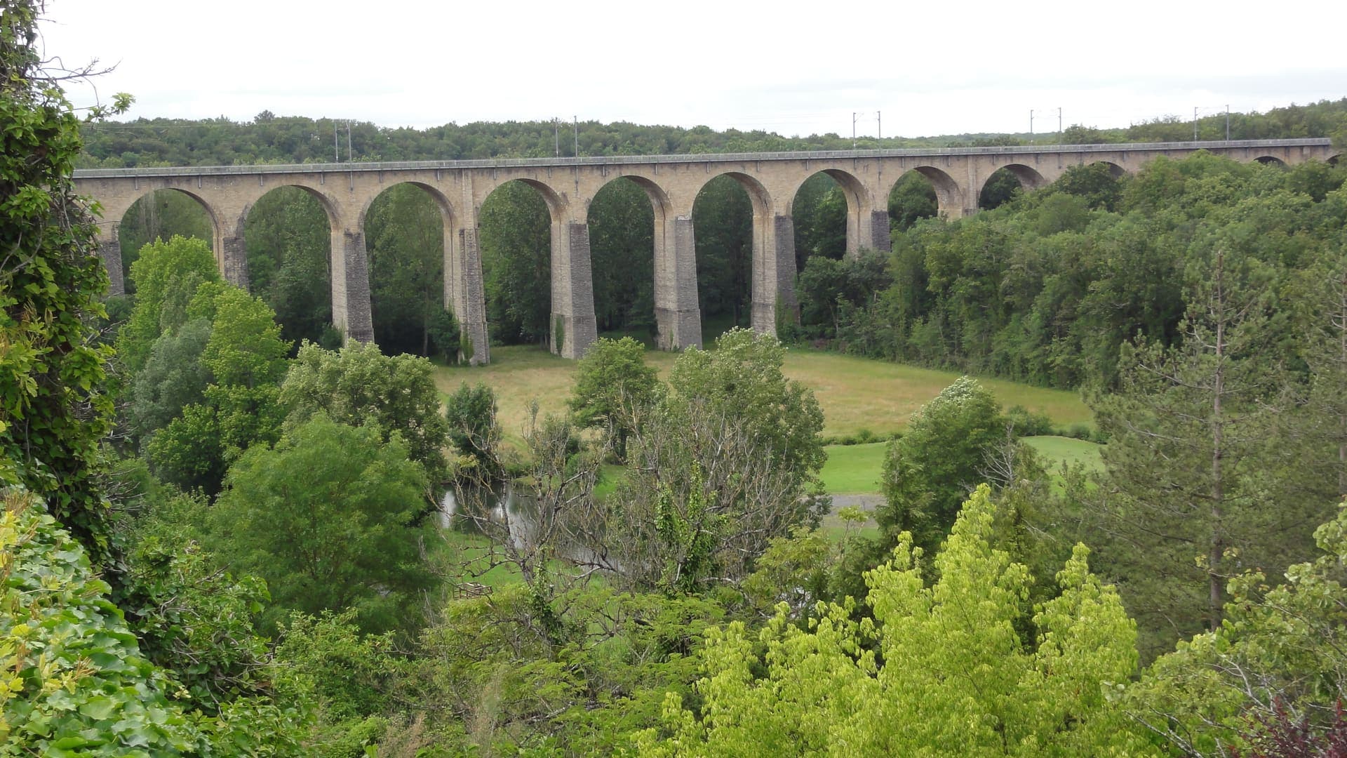 Le viaduc ferroviaire de Lusignan, arches de pierre dominant la vallée boisée