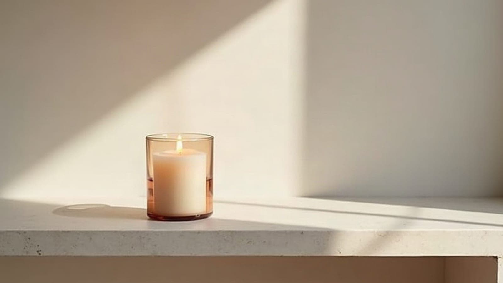 Un cierge allumé posé sur une console de pierre claire, flamme douce et régulière