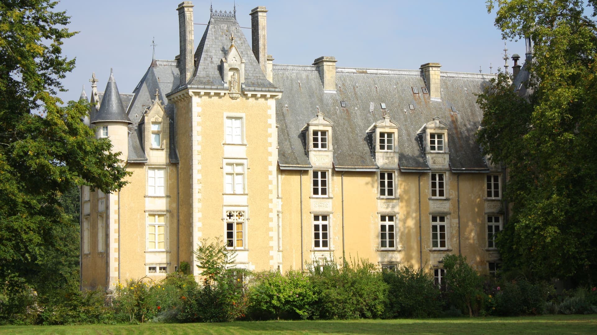 Le château de Saint-Julien-l'Ars, façade claire et toitures d'ardoise au milieu de son parc